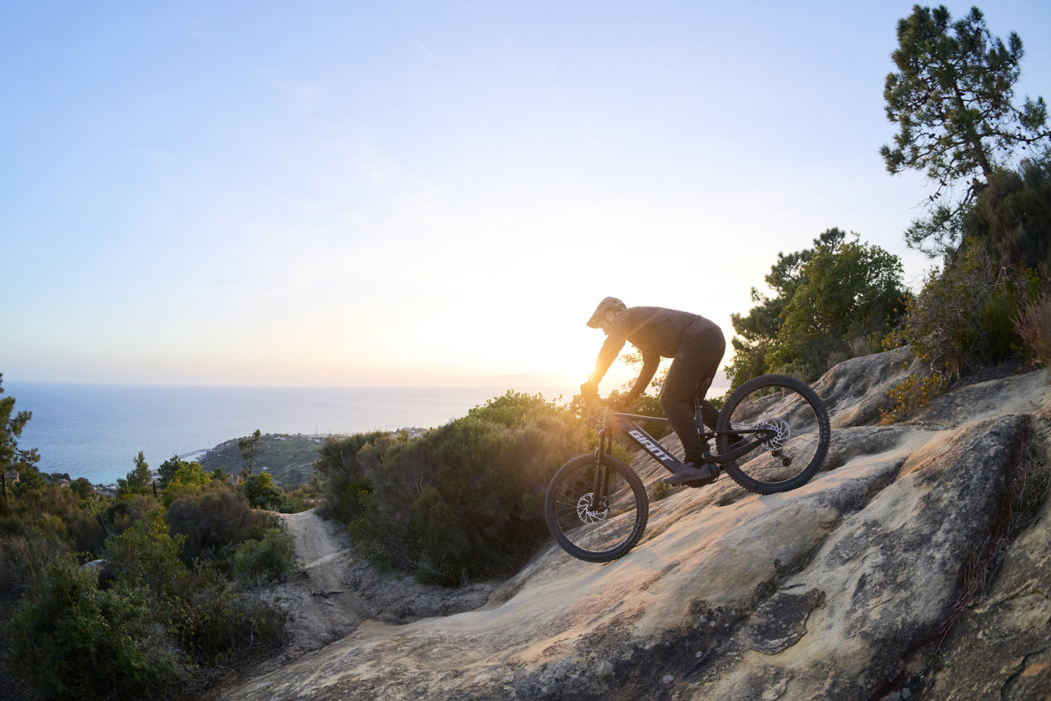 Jezdec na Giant Stance E+ sjíždí technický skalnatý sjezd na trailové stezce